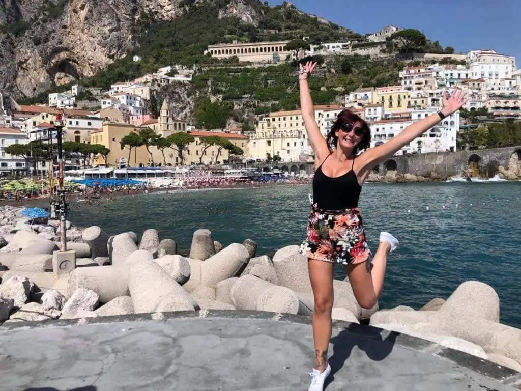 Amalfi Coast Road Trip - girl jumping in the air with the back drop of the amalfi coast iconic houses