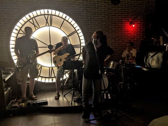 Malta 3 days - Rock Band playing on stage in front of a large lit up victorian clock face