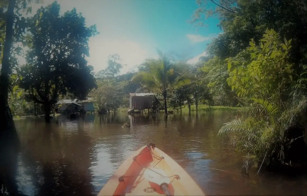 Top adventurous things to do in Costa Rica - tip of a kayak as it appraches a wooden jungle cabin