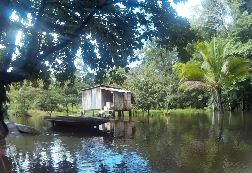 Top adventurous things to do in Costa Rica - a wooden shack at the edge of a narrow canal in the jungle 