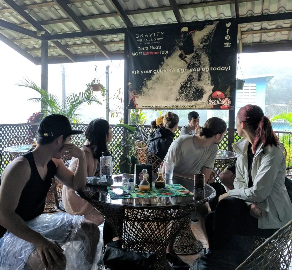 Pros and Cons of Group Tours - a group of travellers looking away from the camera towards a sign that advertises an extreme sport 