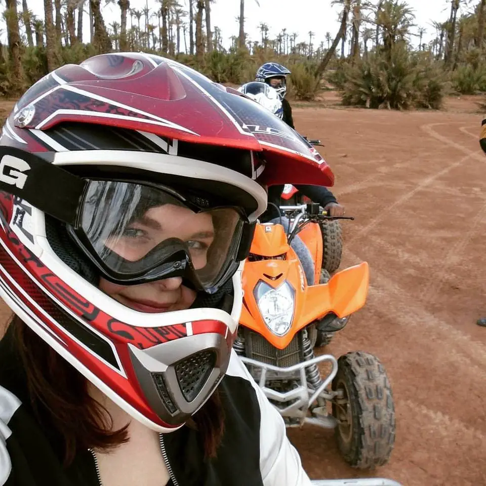 Epic things to do in Marrakech - girl smiling with helmet on a quad bike in the palm coves of Marrakech