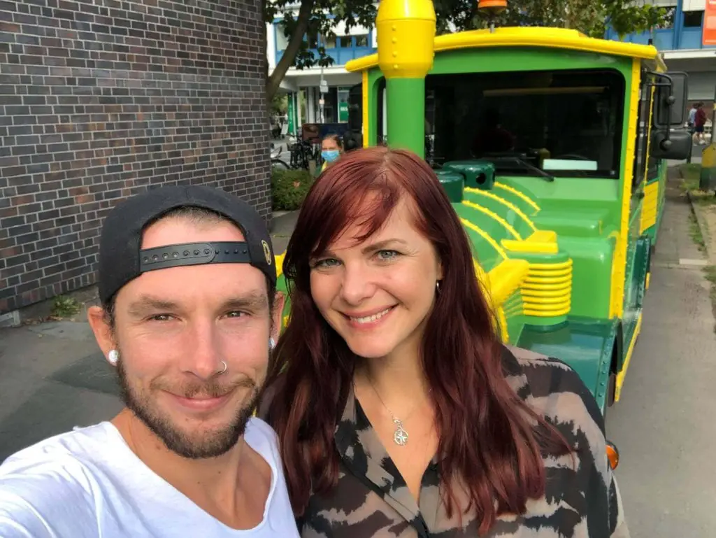 Things to do in Cologne Old Town - a happy couple stood infront of the green and yellow mini sight seeing train 