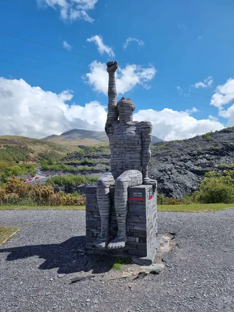 Zip World Karts - a statue set against the welsh slate mountains with a single arm in the air 