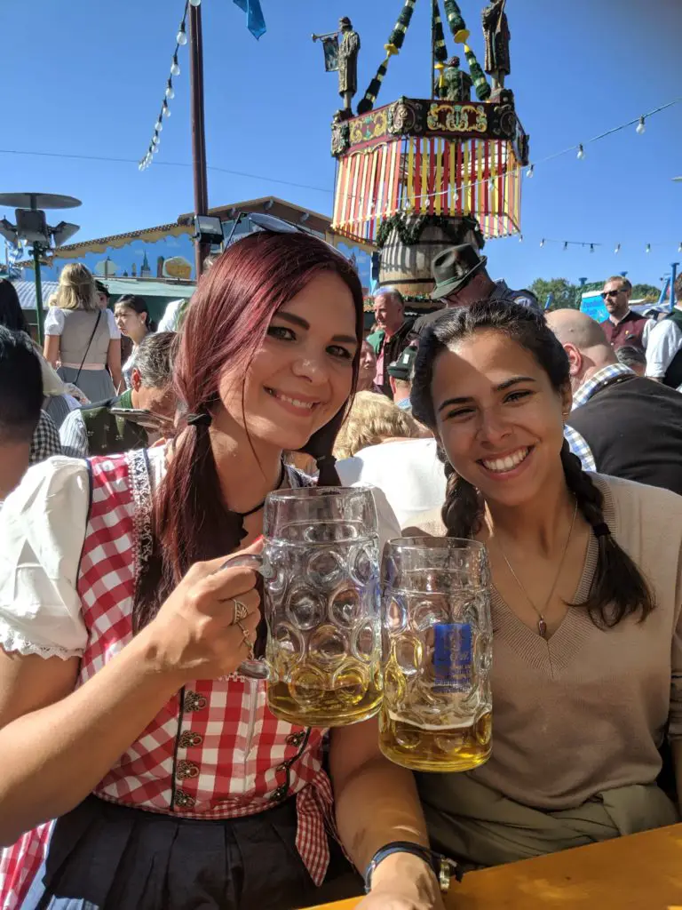 Munich beer festival - beer tent with women drinking steins and wearing Dirndl